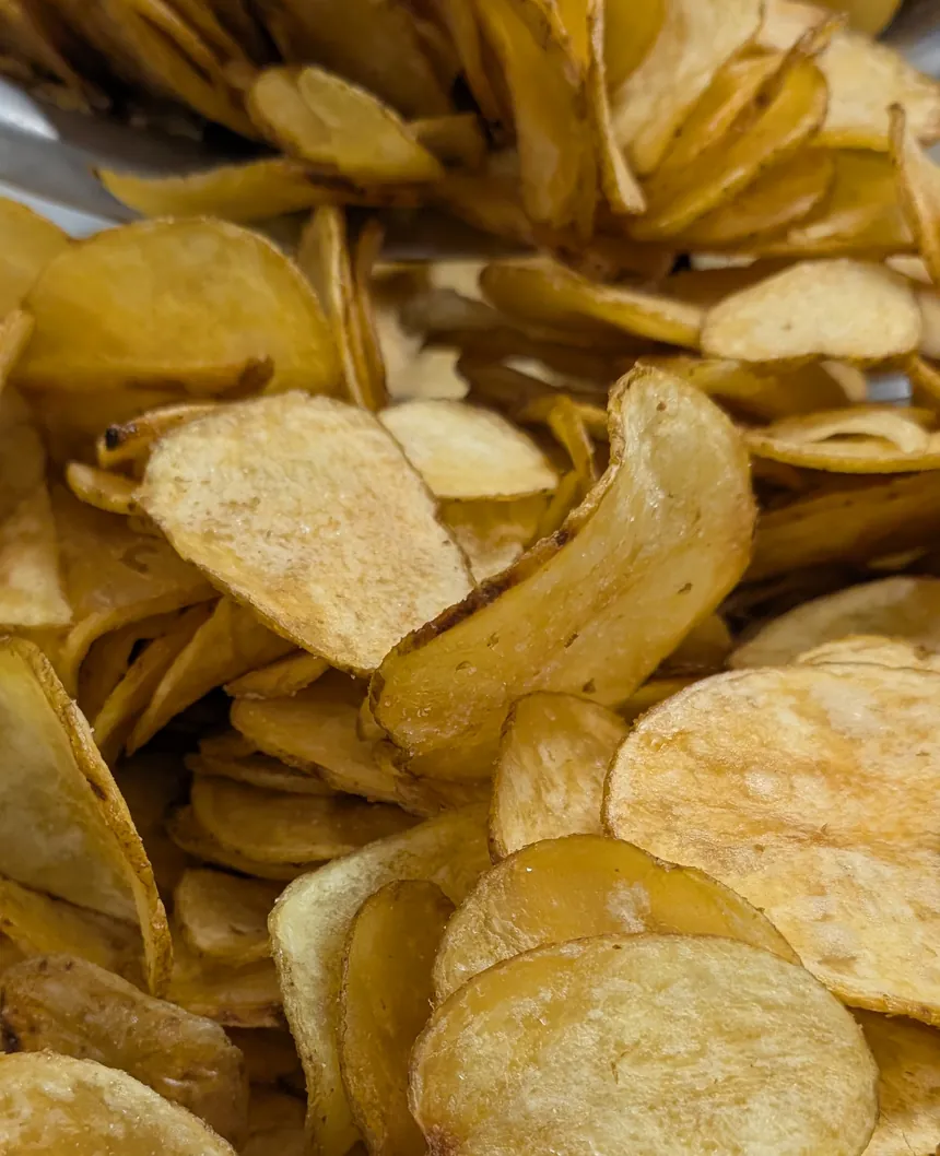 A heap of golden tallow-cooked FAT Chips in a steel bowl